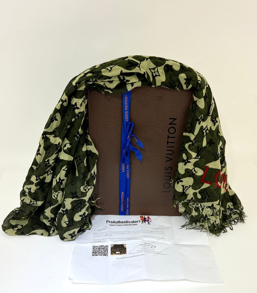 Green patterned scarf draped over a brown Louis Vuitton box with a white background