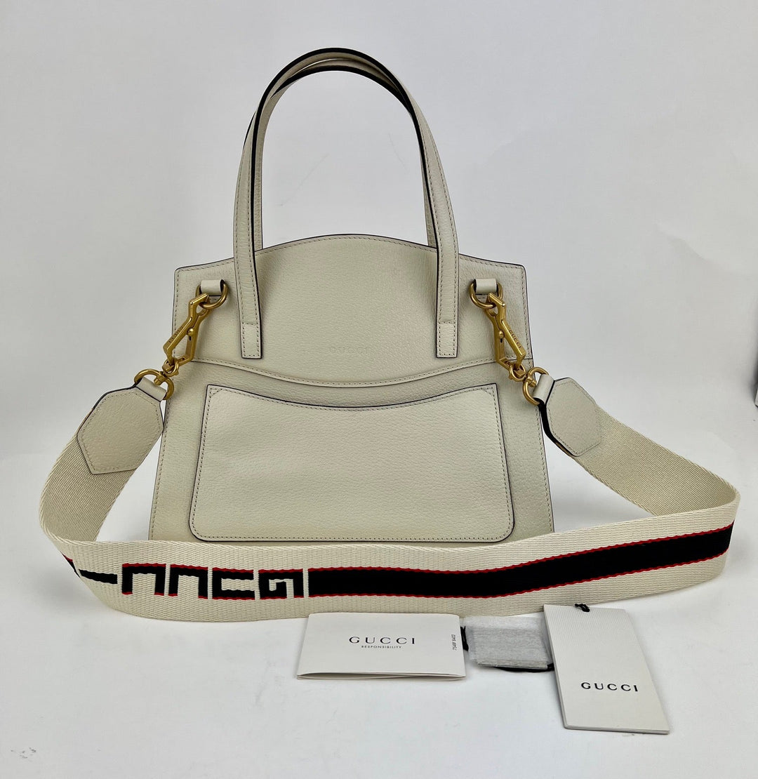 Beige handbag with a Gucci logo strap on a white background