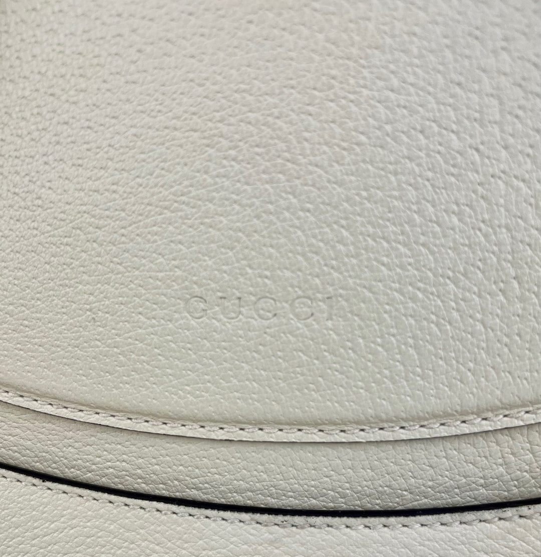 Close-up of Gucci logo on light gray leather surface