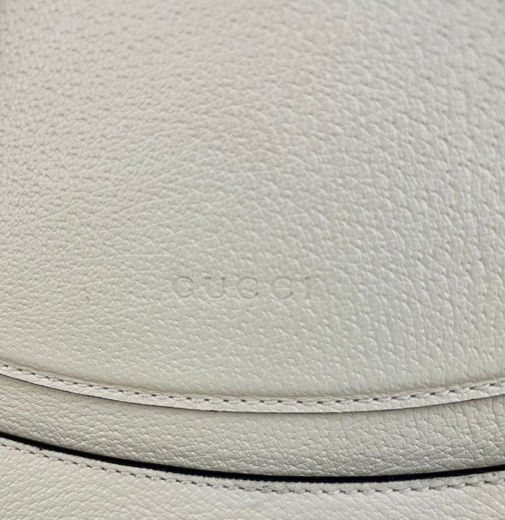 Close-up of Gucci logo on light gray leather surface