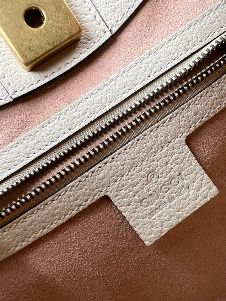 Close-up of a leather bag with a zipper and visible brand logo.