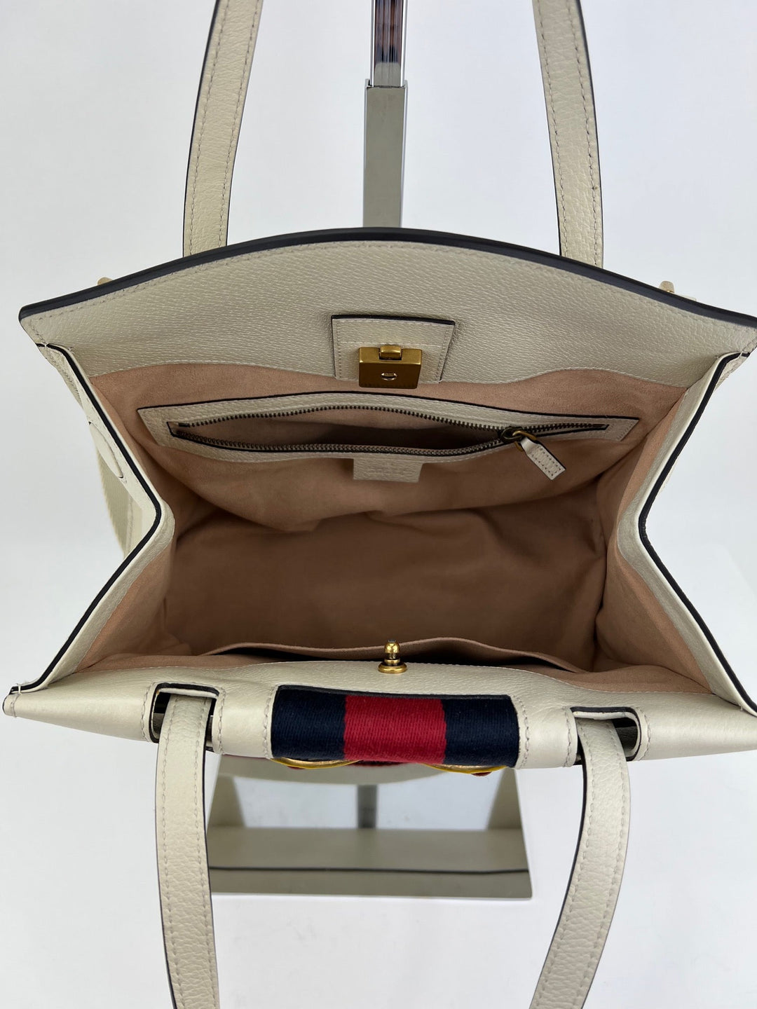 Open beige handbag with visible interior and brand logo on a white background