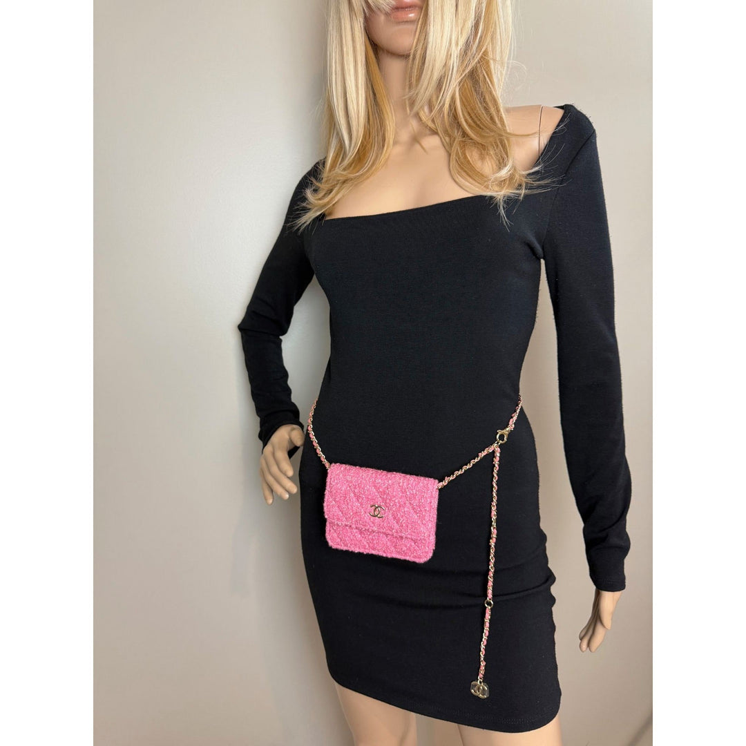 Black dress with a pink purse on a mannequin against a neutral background