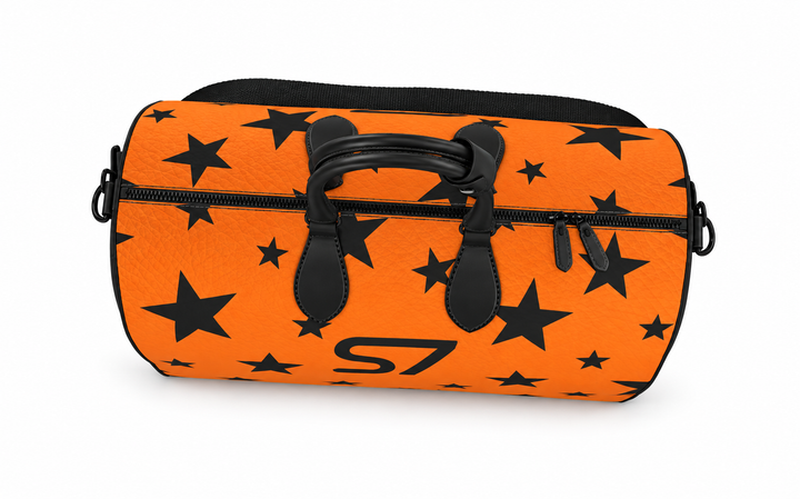 S7 Solar Noir orange leather duffle bag with scattered black five-point stars, a centered black S7 monogram and black handles and end panels.