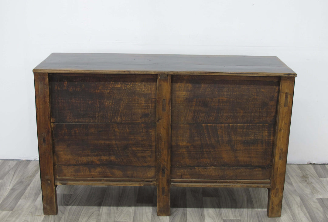 Wooden sideboard with a dark finish on a light wooden floor against a white wall.