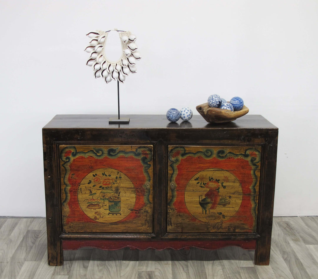 Wooden cabinet with decorative doors featuring animal illustrations, placed on a light wooden floor against a white wall.