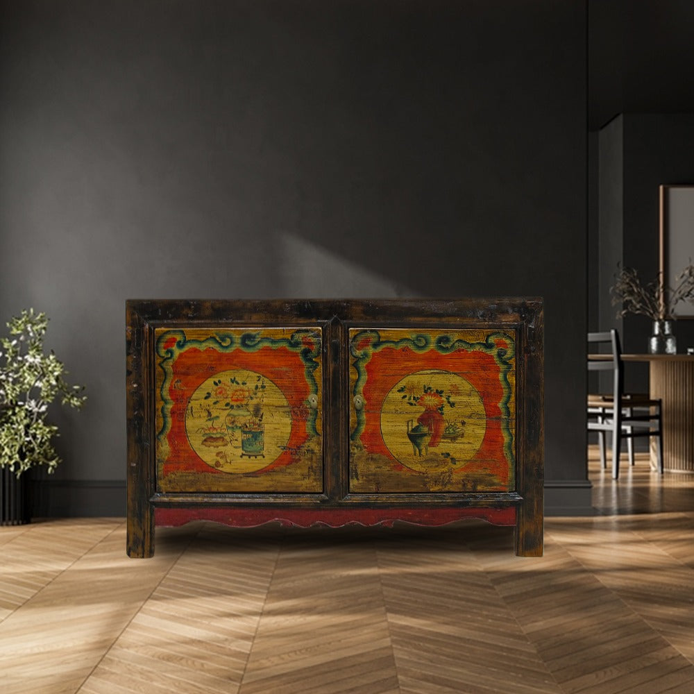 Decorative wooden cabinet with colorful artwork in a room with dark walls and wooden floor.