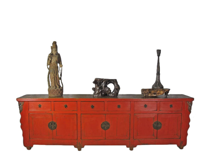 Red wooden sideboard with decorative items on a white background