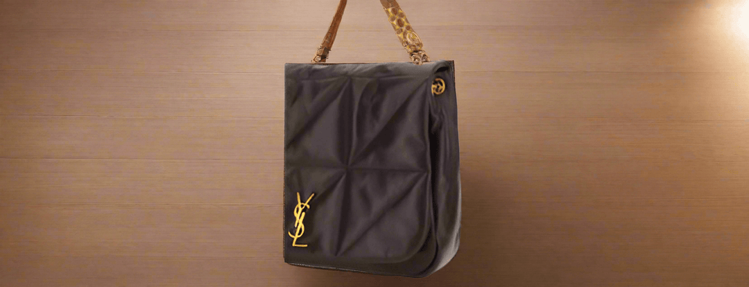 A brown leather Saint Laurent shoulder bag with a gold chain strap displayed in a store.