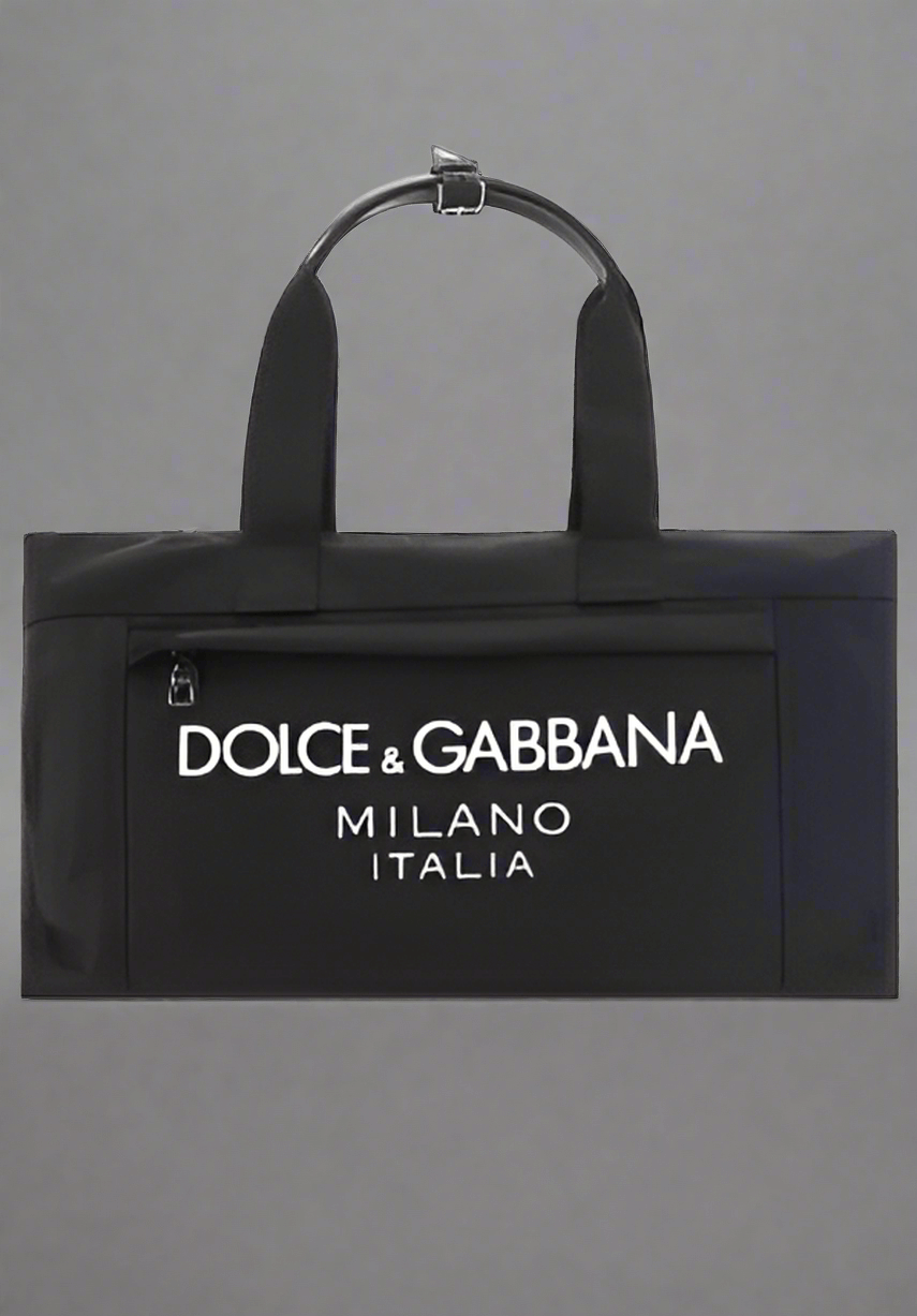 Travel Bag by Dolce&Gabbana, top closure with double-slider zipper, zippered welt pocket on back, iconic brand monogram printed in contrast on front, patch pocket on front panel, removable and adjustable nylon shoulder strap.

