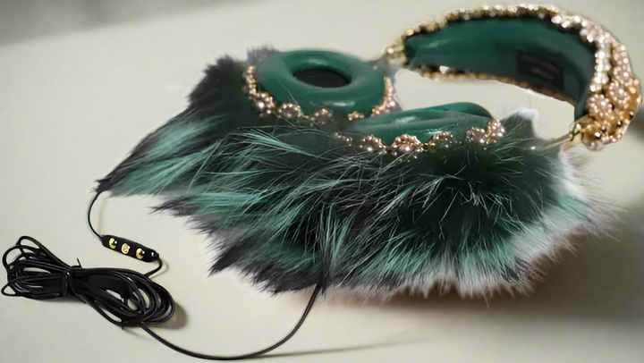 Teal feathered headphones with decorative chain on a white background