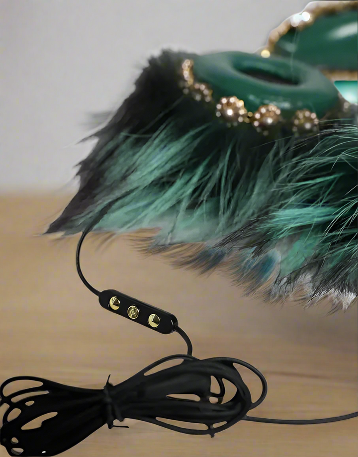 Green feathered object with a black cord on a white background