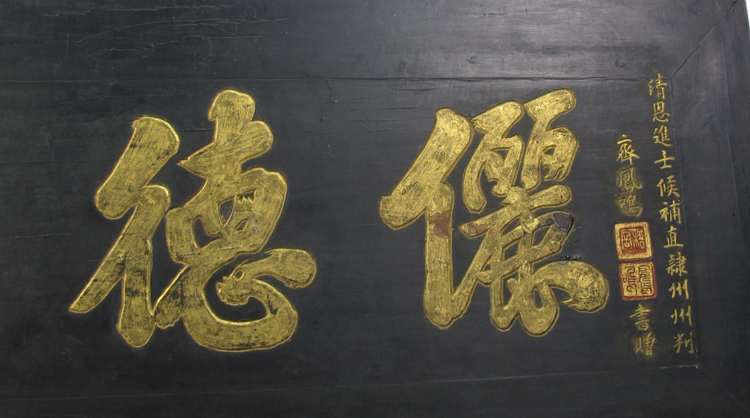 Two large gold Chinese characters on a black background with calligraphy.