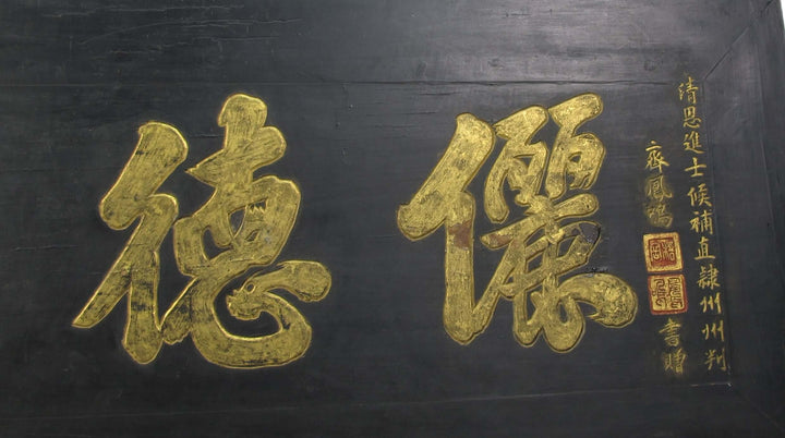 Two large gold Chinese characters on a black background with calligraphy.