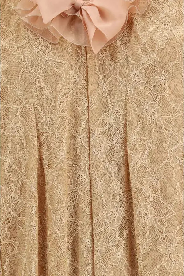 Close-up of beige lace fabric with a large pink bow at the top.