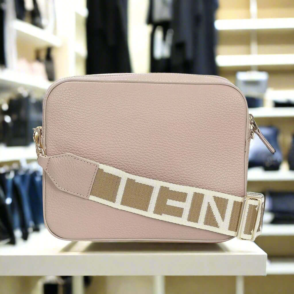 Pink crossbody bag with a beige strap on a white background