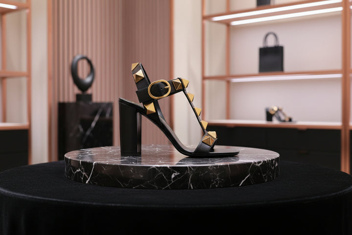 Black sandal with gold studs on a white background