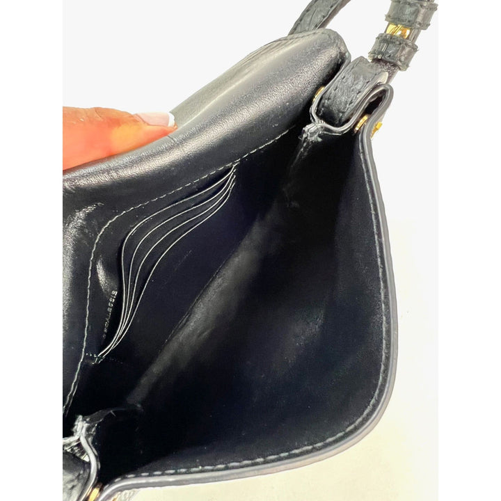 Close-up of a black leather handbag with visible stitching on a white background