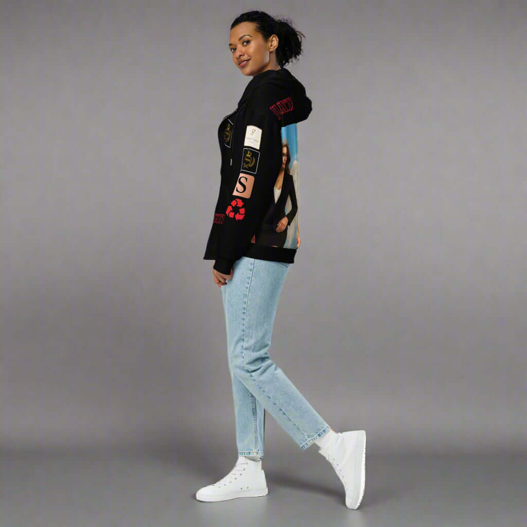 Person wearing a black hoodie with graphic designs and light blue jeans on a white background