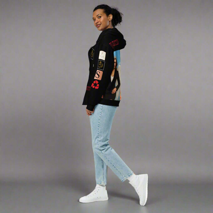 Person wearing a black hoodie with graphic designs and light blue jeans on a white background