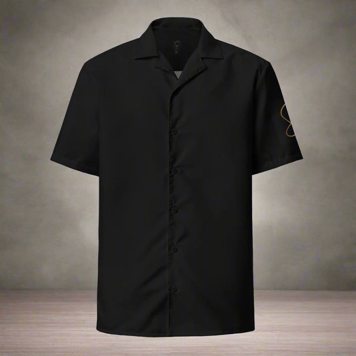 A black unisex button shirt with short sleeves, featuring a small round neckline and a front pouch. The shirt is designed with a graphic of salsa dancers on the front.
