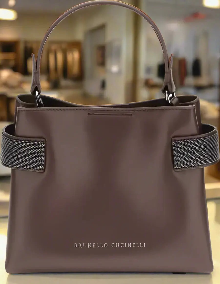 Brown handbag with green straps on a white background, featuring Brunello Cucinelli branding.