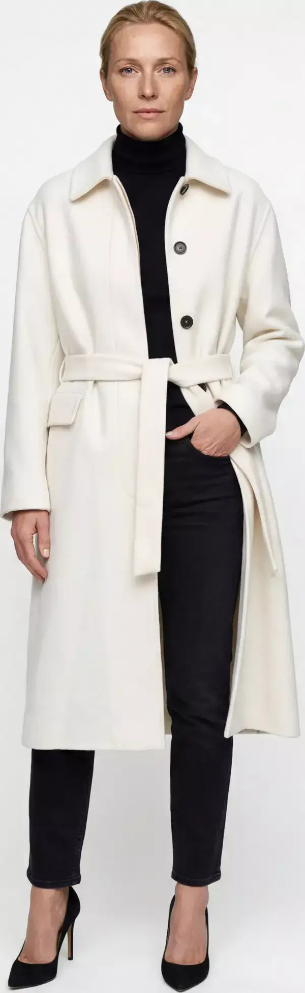 Woman wearing a white coat over a black outfit on a white background
