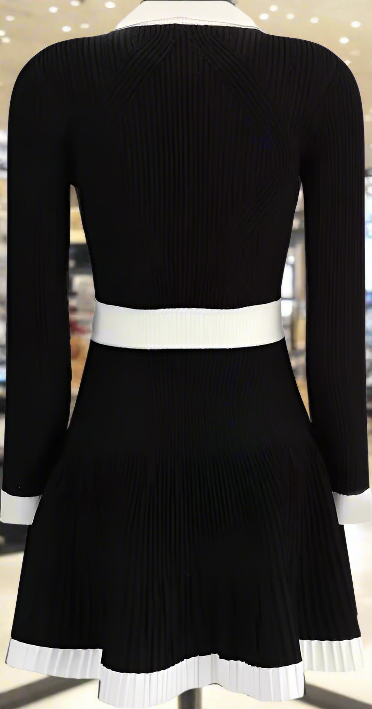 Black dress with white trim on a plain background