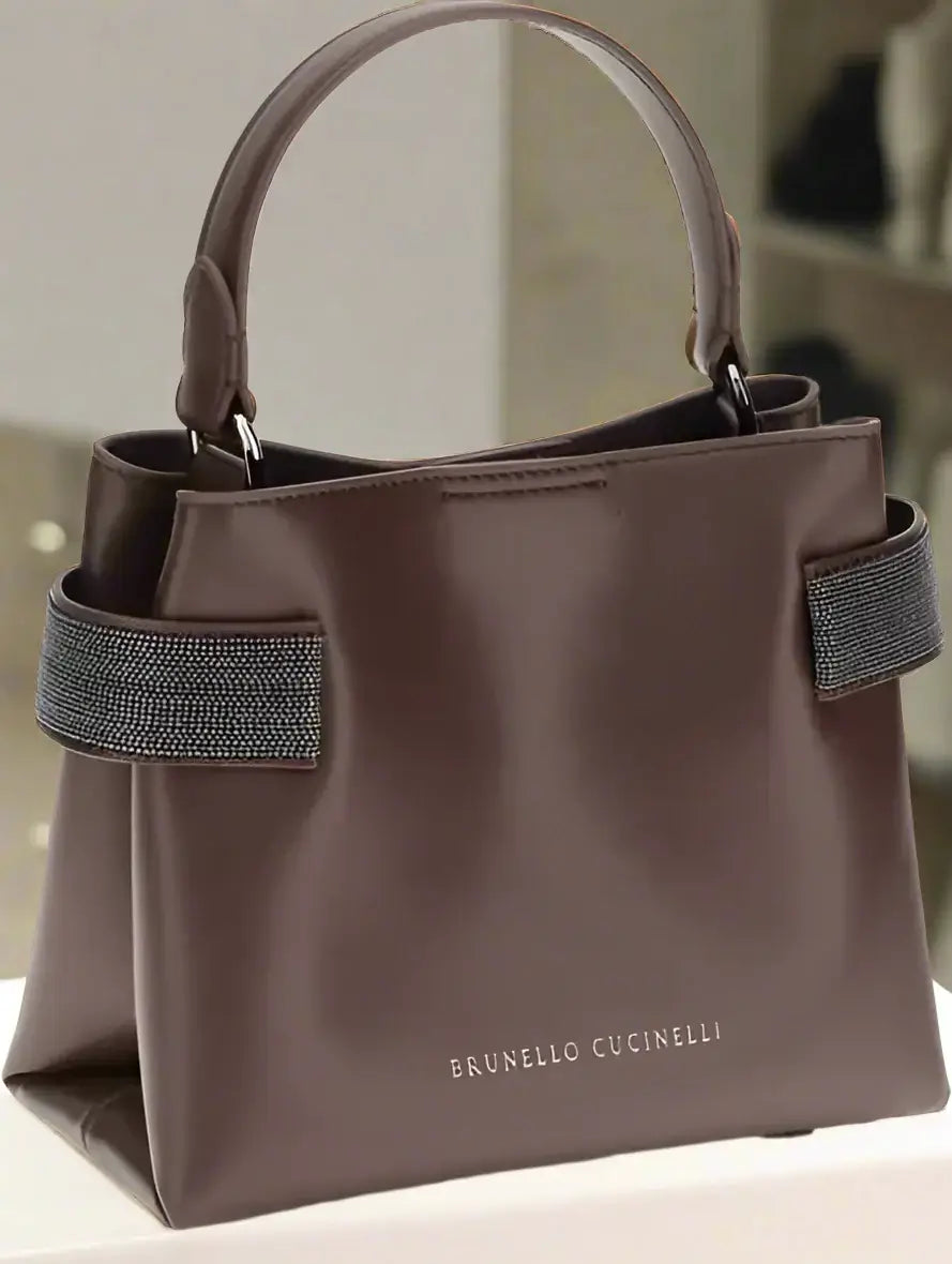 Brown handbag with a textured strap on a white background, featuring the Brunello Cucinelli brand.