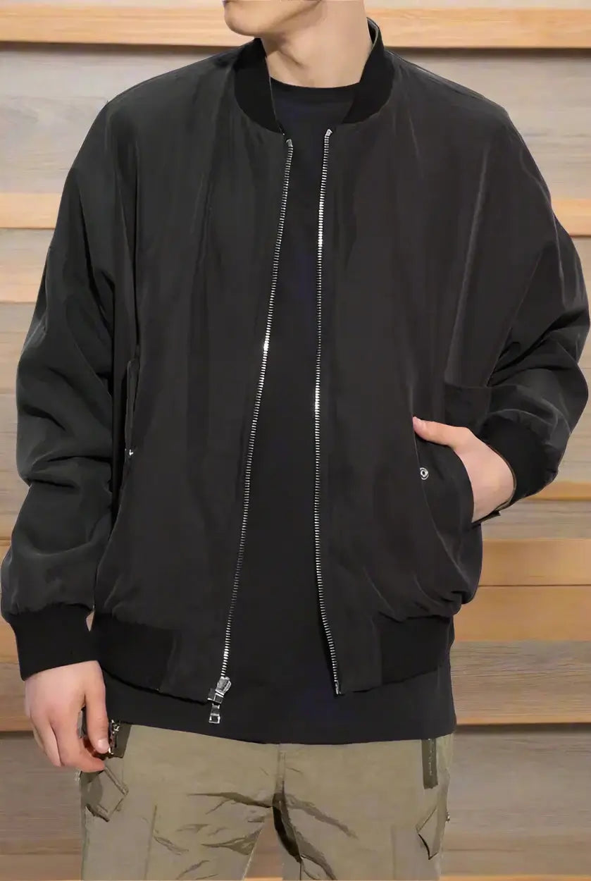 Person wearing a black bomber jacket with a white background