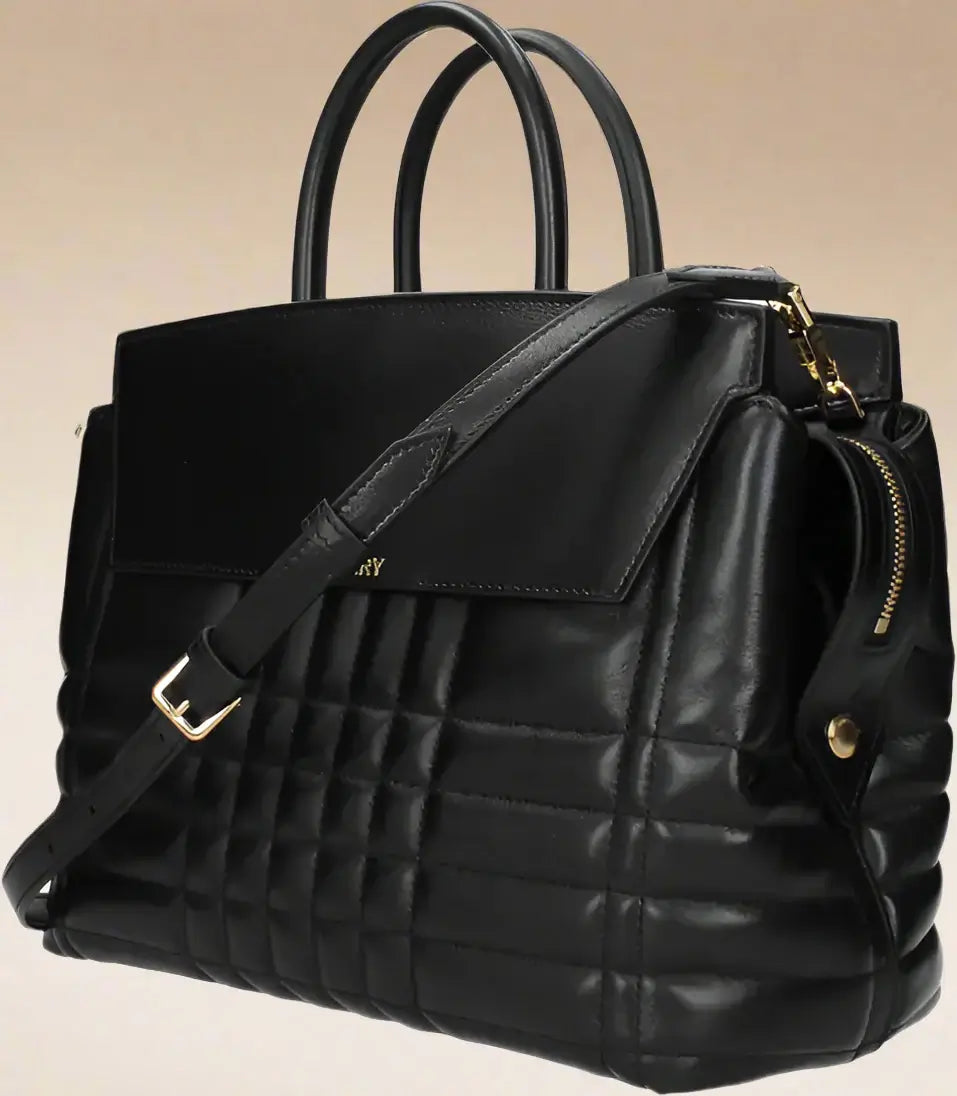 Black quilted handbag with gold accents on a white background