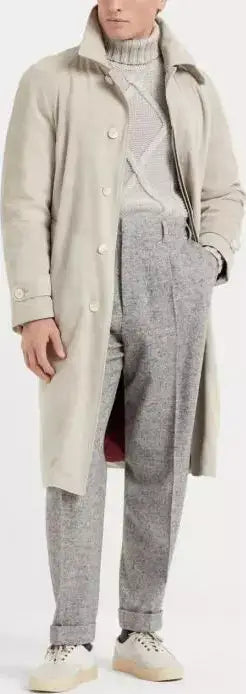 Person wearing a long beige coat over a gray outfit on a white background