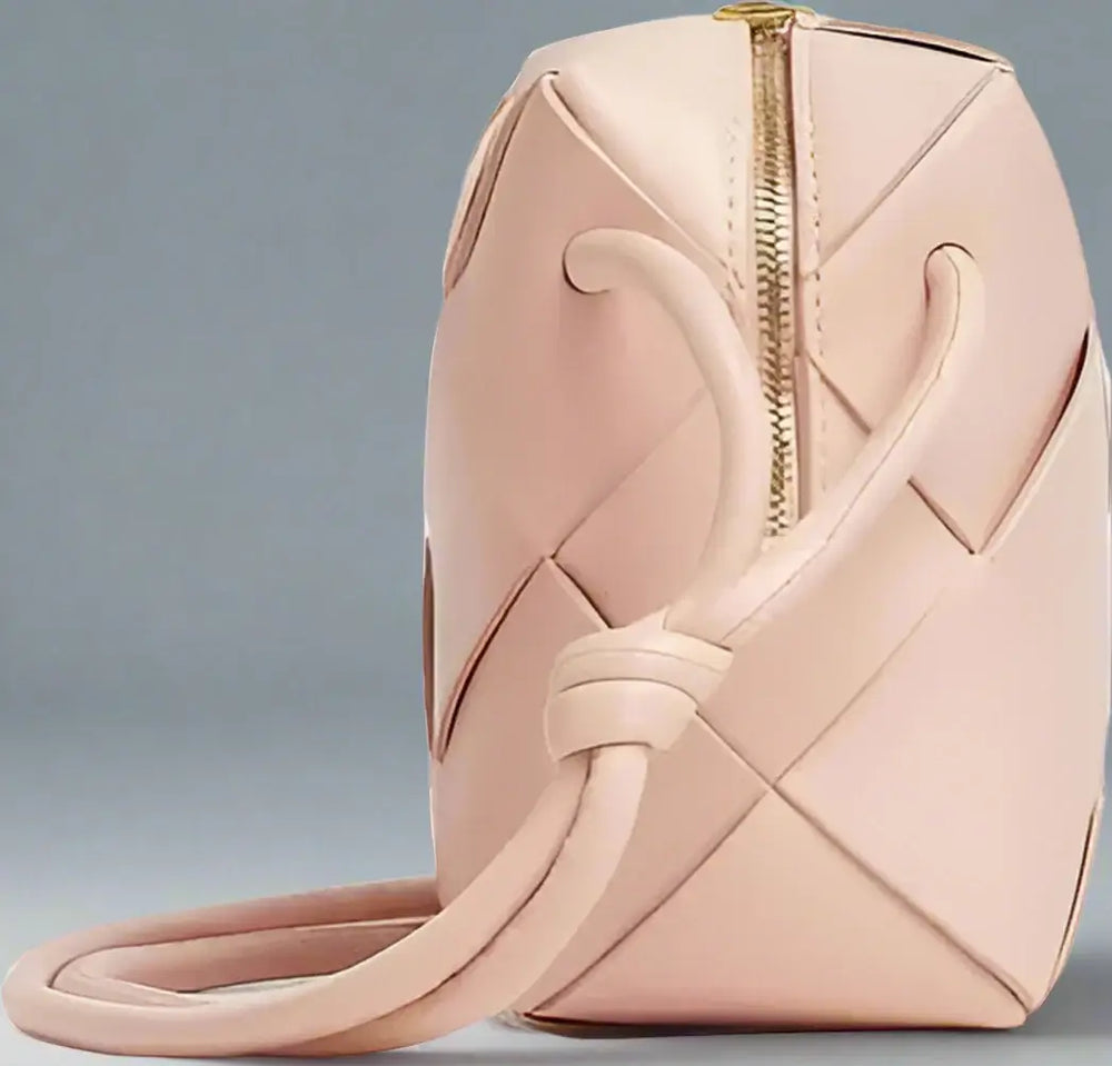 Pink woven handbag with a gold zipper on a white background