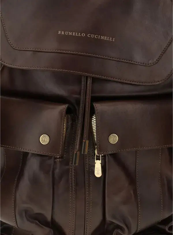 Brown leather backpack with gold zippers and buttons, featuring Brunello Cucinelli branding.
