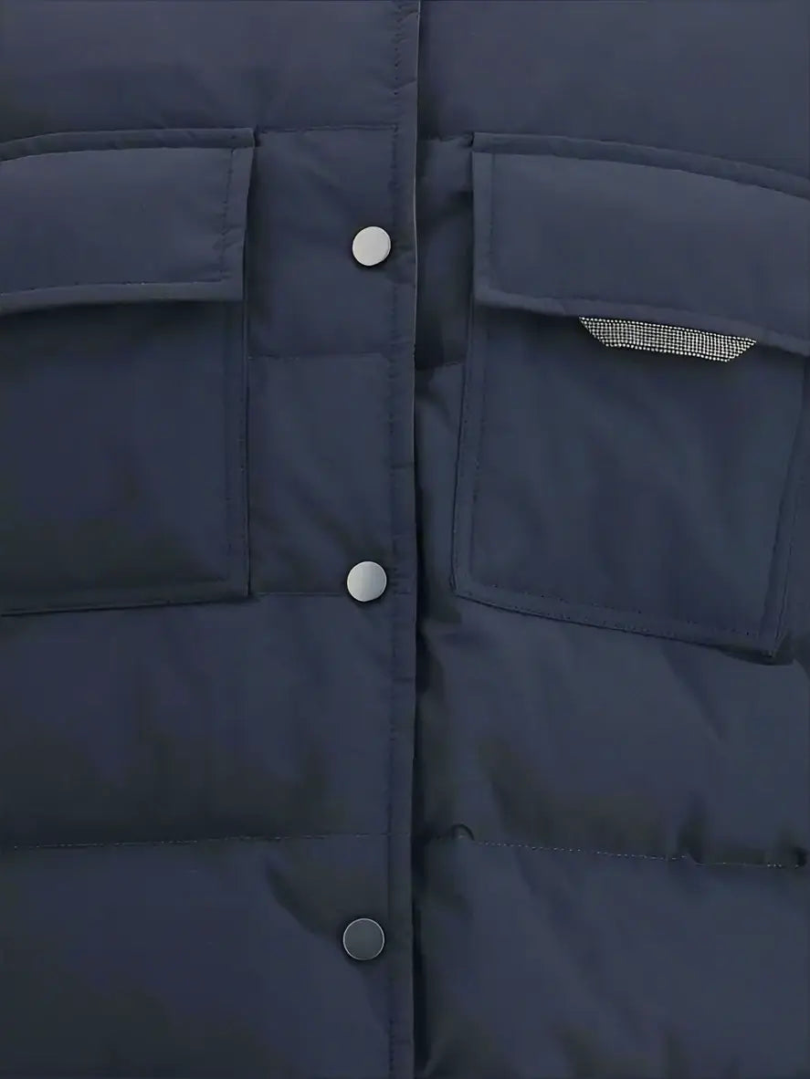 Close-up of a navy blue puffer jacket with buttons and a pocket.