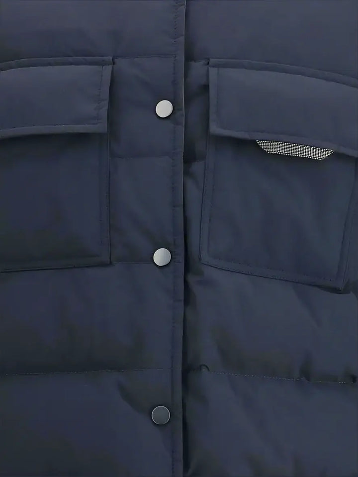 Close-up of a navy blue puffer jacket with buttons and a pocket.