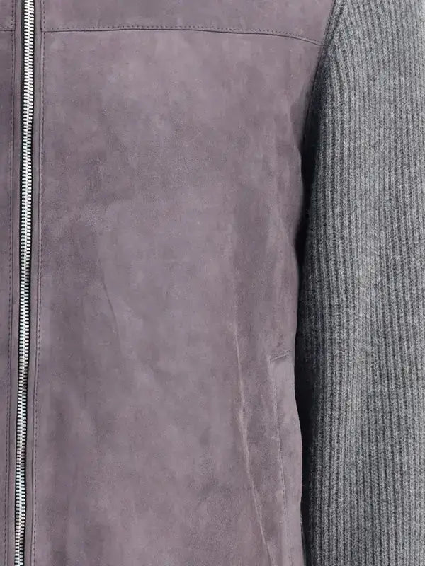 Close-up of a gray leather jacket with a zipper and a textured gray sweater sleeve.