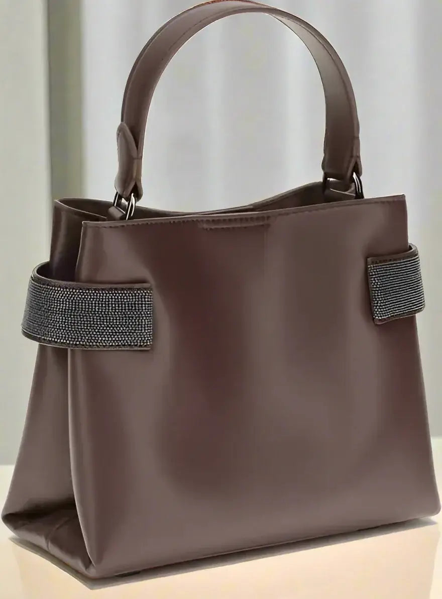 Brown handbag with a decorative strap on a white background
