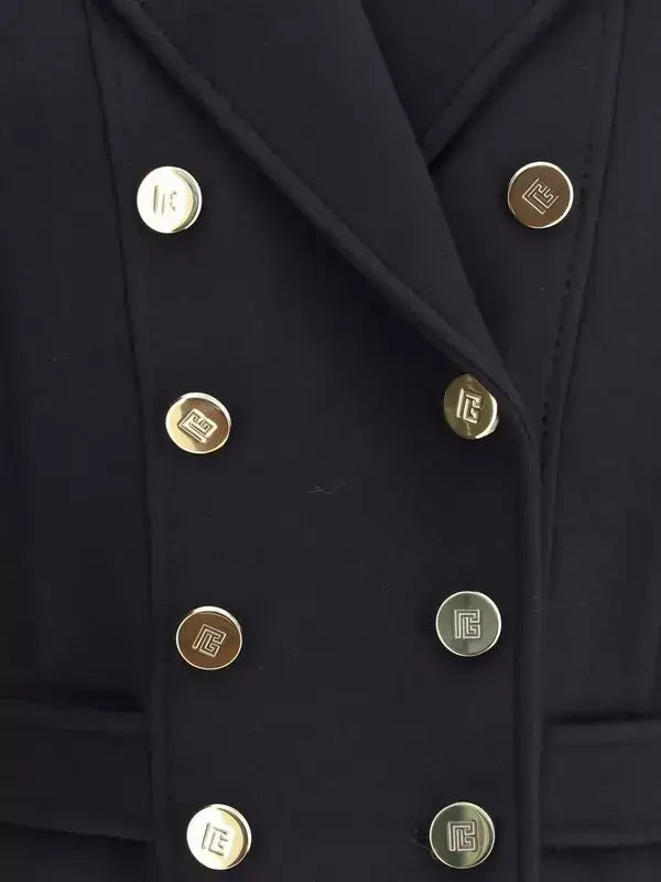 Close-up of a black coat with gold buttons on a dark background