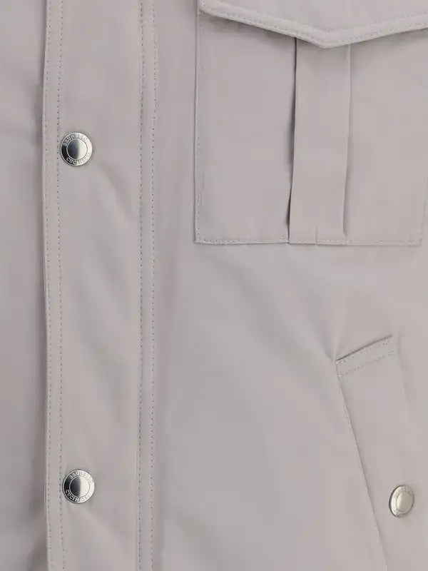 Close-up of a light gray jacket with buttons and a pocket