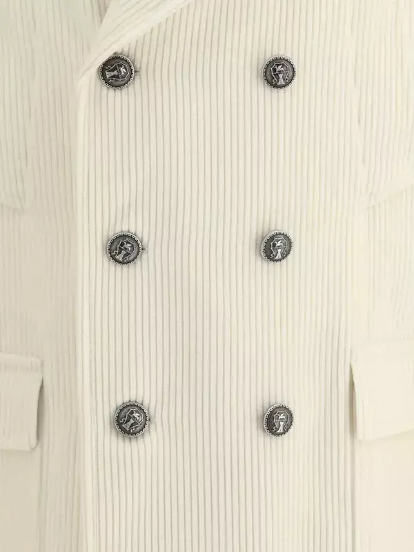 Close-up of a ribbed cream-colored jacket with decorative buttons.