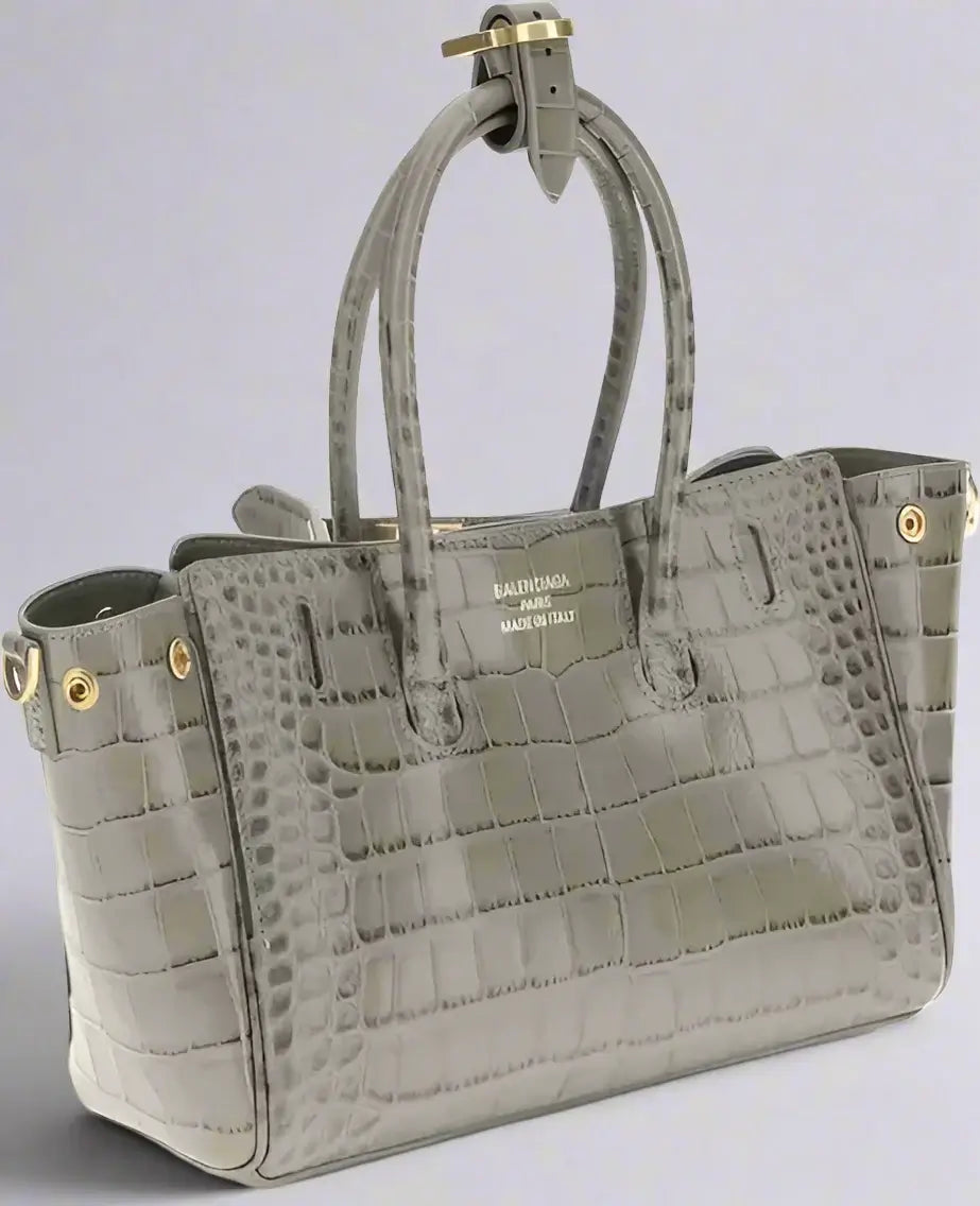 Gray crocodile-patterned handbag with gold accents on a white background