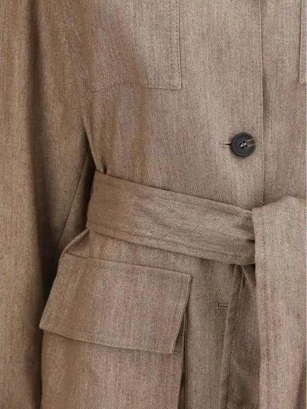 Close-up of a beige trench coat with a button and belt detail.