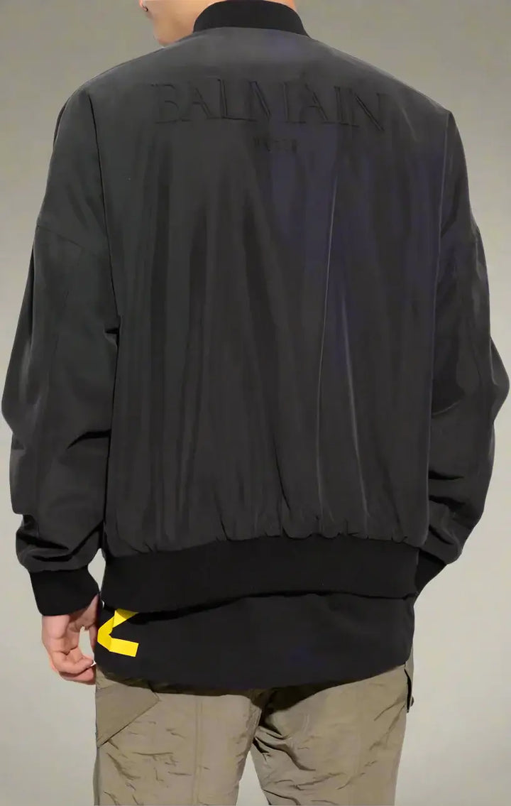 Black jacket with 'Balmain' branding on the back, worn by a person.