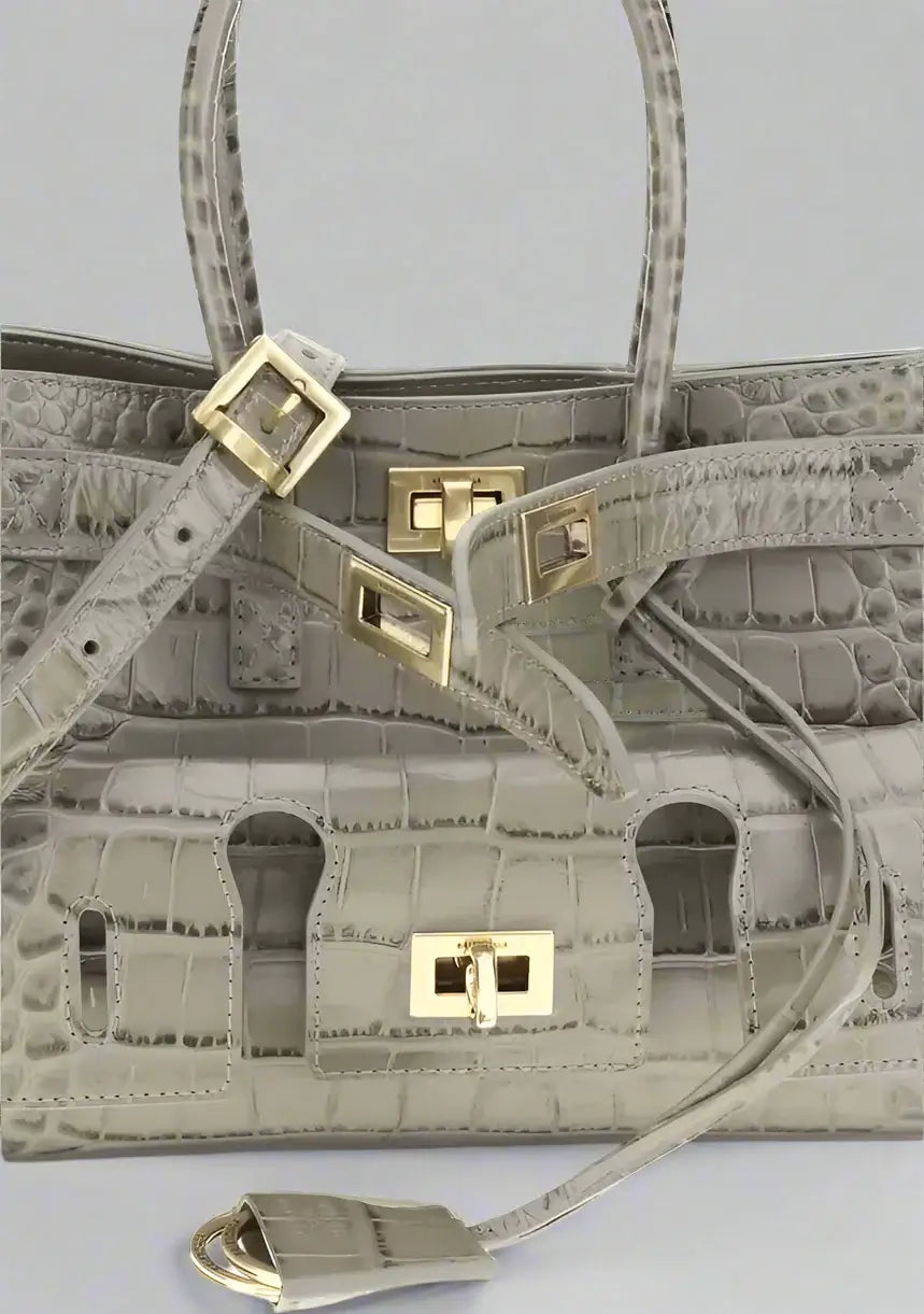 Gray textured handbag with gold hardware on a light gray background