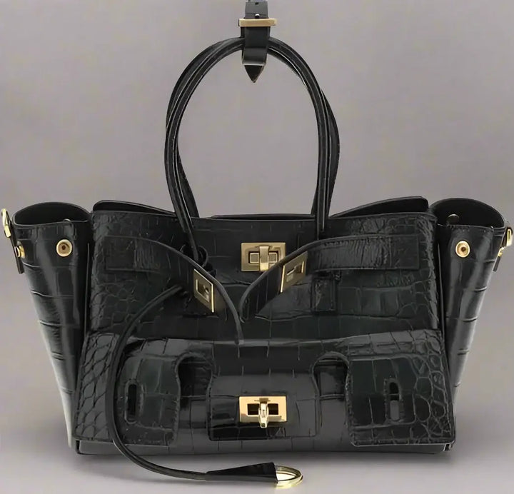 Black crocodile-patterned handbag with gold hardware on a white background
