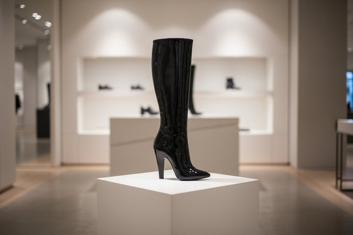 Black patent leather knee-high boot on a white background