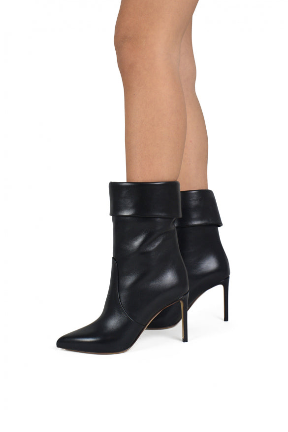 Black high-heeled ankle boots worn by a person on a white background