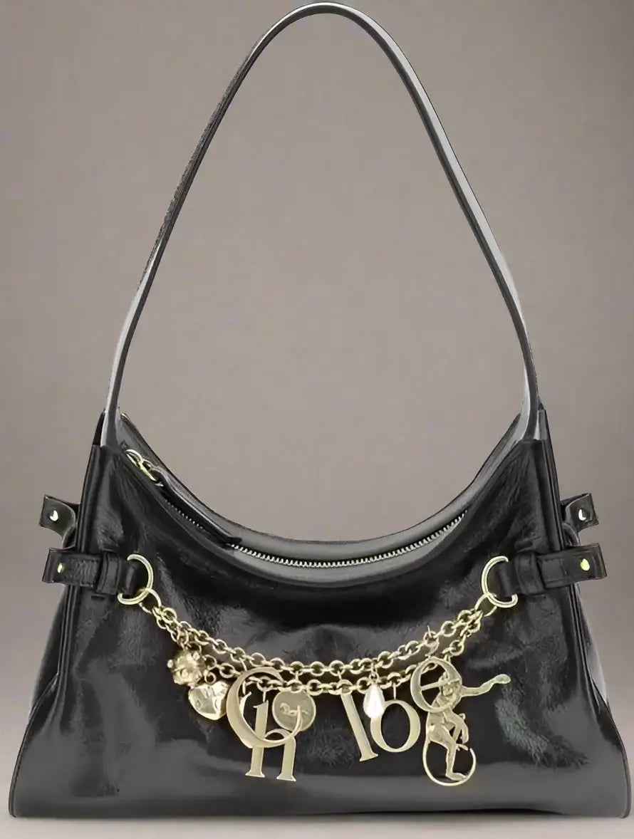 Black handbag with gold chain and charms on a white background