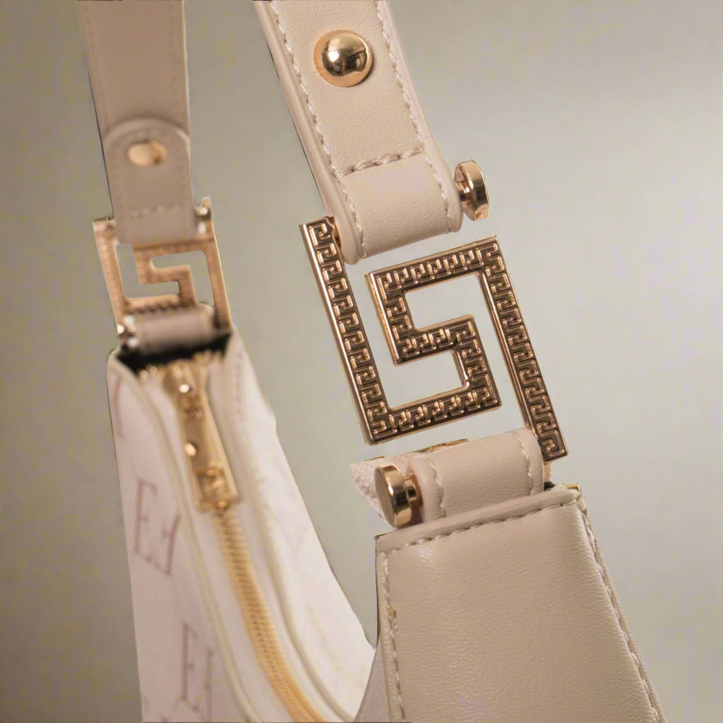 Close-up of beige handbag strap with gold hardware on a white background